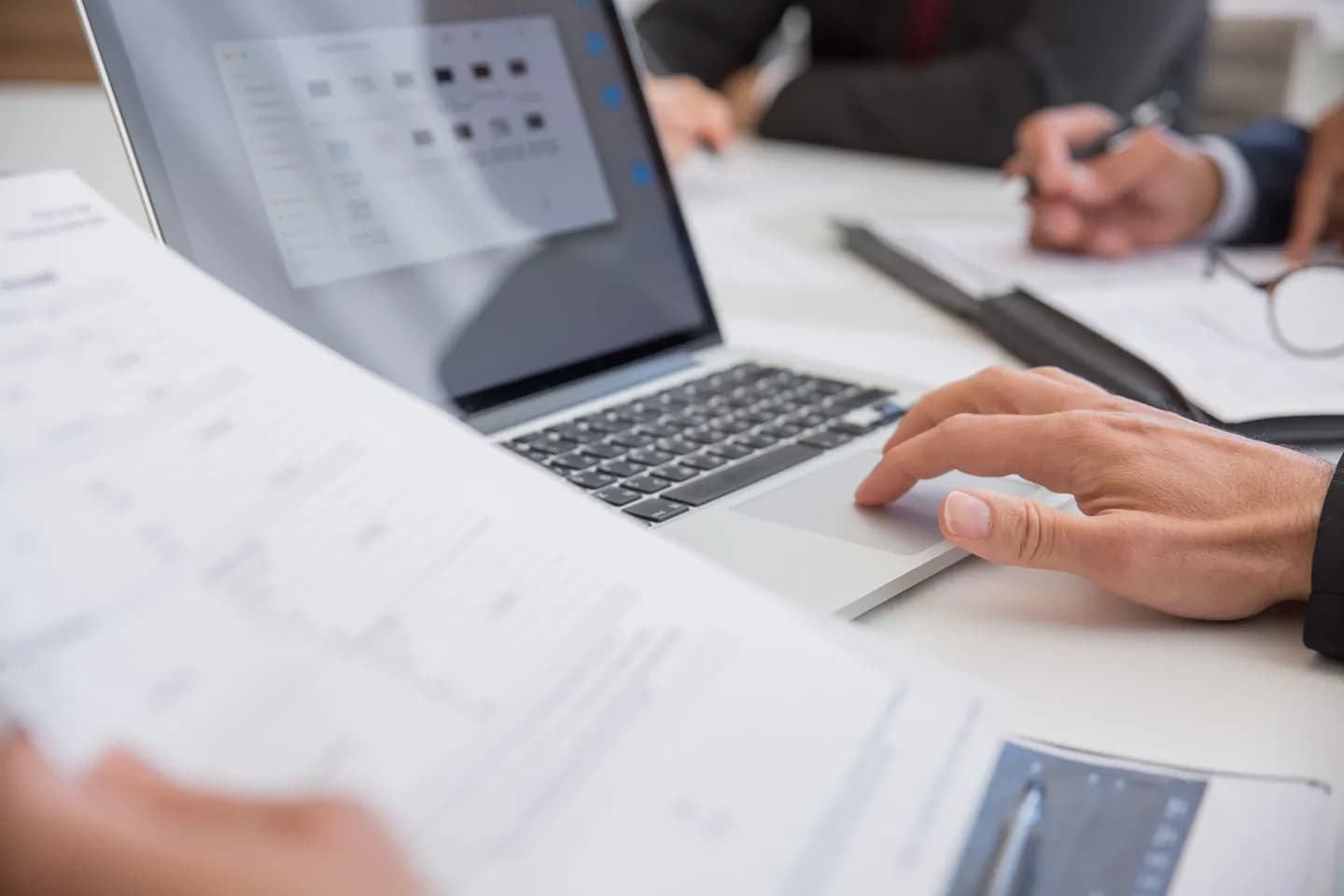 how to copy text from image: hands working with a laptop and paper documents